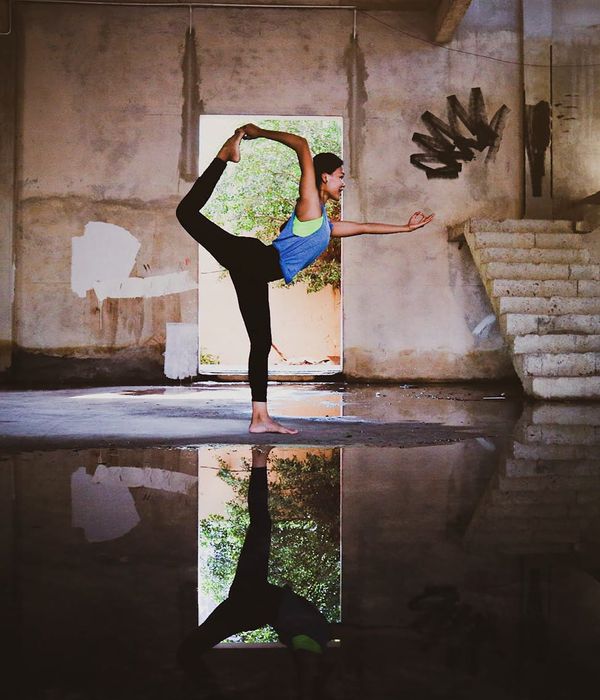 Woman in a calm yoga pose in a dark room with cyan light.
